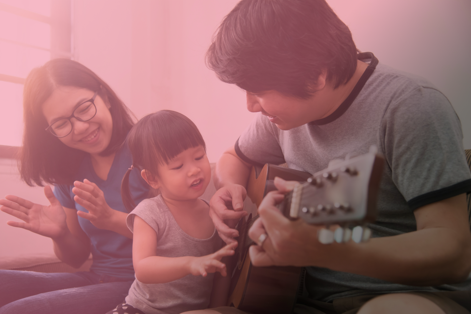 A family enjoys listening to a dad playing Guitar.