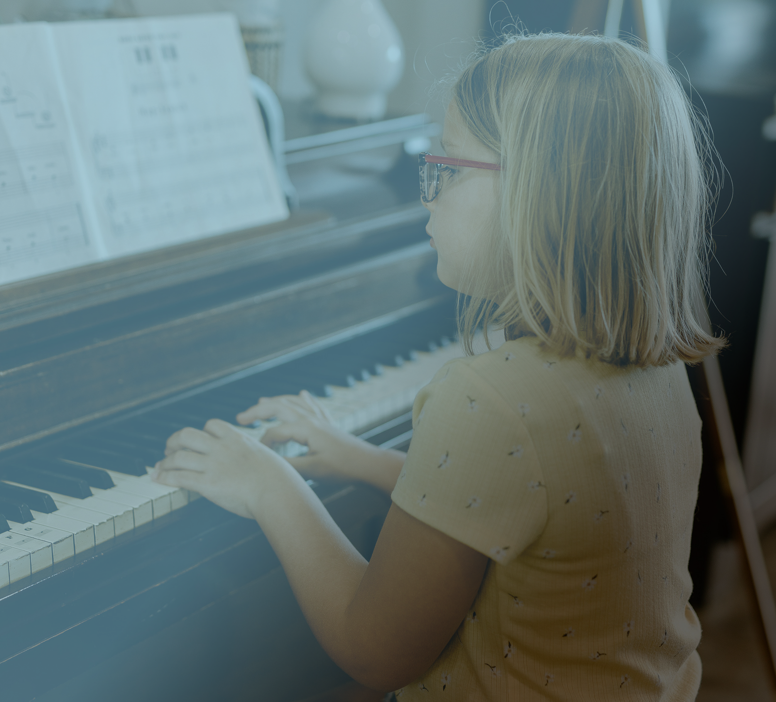 A young girl sitting at the piano learning to play a song.